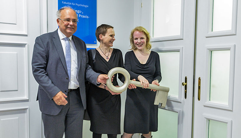 Rektor Heinz W. Engl, Dekanin Barbara Schober und Leiterin Ricarda Nater-Mewes mit einem großen goldenen Schlüssel in der Hand bei der Eröffnung der Räumlichkeiten der Forschungs-, Lehr- und Praxisambulanz der Fakultät für Psychologie.