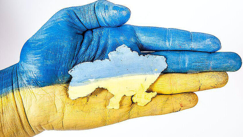 Image of a hand holding the outline of Ukraine in the national colours blue and yellow