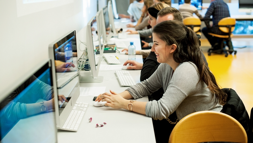 Lachende Studierende sitzt vor einem Computer